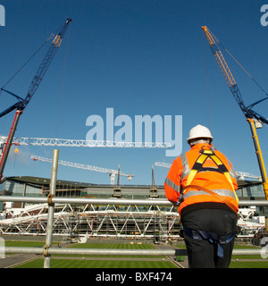 Banksman watches as two cranes working in tandem begin to lift roof trusses on to Centre Court  All England Lawn Tennis Club. Stock Photo