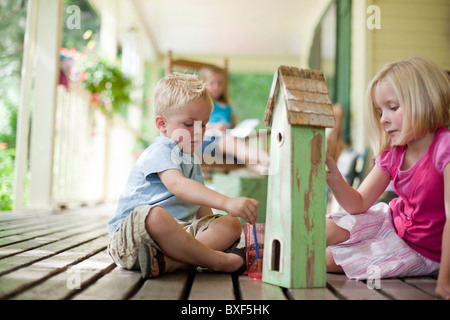 Brother and sister painting birdhouse together Stock Photo