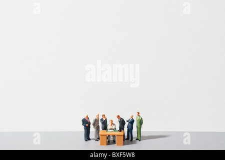 Figurines of people standing around desk Stock Photo