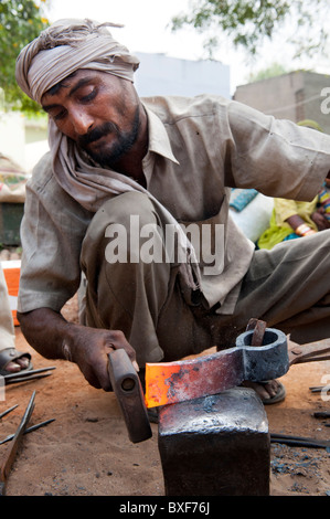 Gadia Lohar. Nomadic Rajasthan man forging axe heads. India's wandering blacksmiths. India Stock Photo