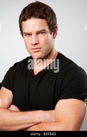 Young muscular strong fit healthy man with arms folded Stock Photo