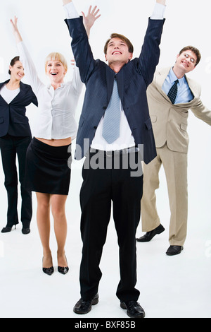 Happy business team are standing and raising hands upwards Stock Photo