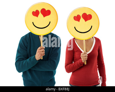 young adult woman and man holding emoticon with red hearts on white background. Horizontal shape, front view, waist up Stock Photo