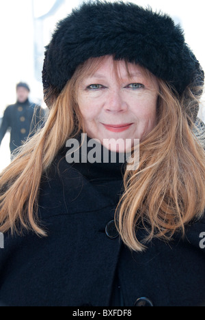 mature woman looking pleased in a black furn hat in the snow. Stock Photo