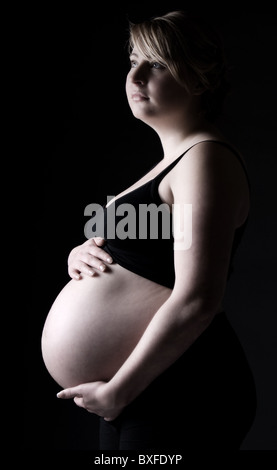 Stunning Low Key Shot of a Heavily Pregnant Blonde Girl Stock Photo