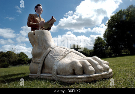 A Sotheby's auctioneer with a gigantic marble foot from a Roman statue at a sale of garden statuary Stock Photo