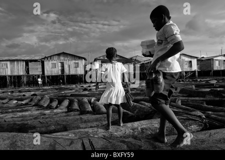 Displaced children walk over the wooden logs in the stilt house area in Tumaco, Nariño dept., Colombia. Stock Photo