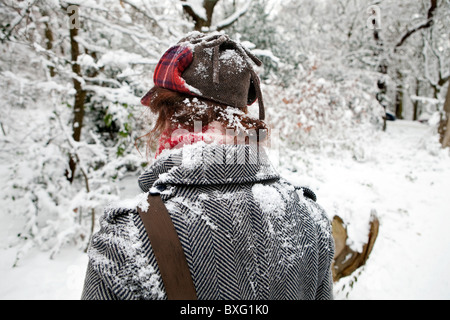Rear view of woman walking in snowy landscape covered in snow. Stock Photo