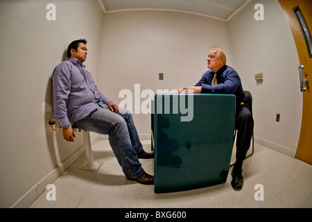 A handcuffed felony suspect is questioned by a Santa Ana, CA, police detective in a specialized interrogation room. Stock Photo