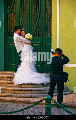 Chinese photographer taking photograph of bride and groom on steps of church in Macau Hong Kong China Stock Photo