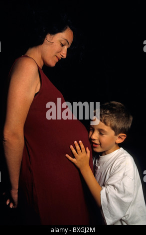 Motherhood. Pregnant woman with her son holding the mother's stomach. Stock Photo