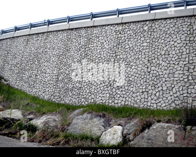 artificial wall to support rural road in rocks and stones of the Dolomites Stock Photo