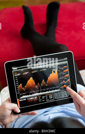 Woman checking financial data on Bloomberg market and finance application on an iPad tablet computer Stock Photo