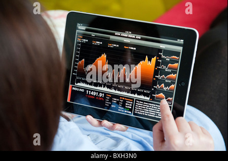 Woman checking financial data on Bloomberg market and finance application on an iPad tablet computer Stock Photo
