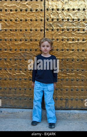 Little girl leaning against a bronze door belonging to the Cathedral de Cordoba, a former medieval mosque in Cordoba, Spain. Stock Photo