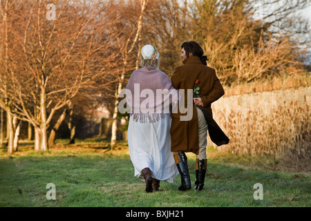 A tour guide dressed as Robert Burns poses in character with a young lady during a romantic walk in a park. Stock Photo