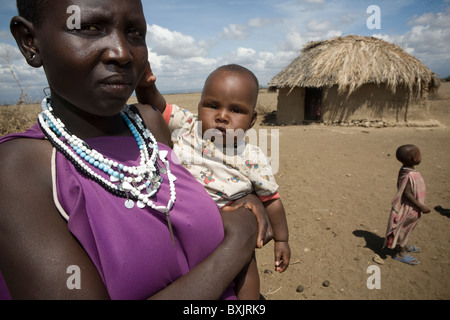 A maasai woman holds a baby outside her house in rural northern Tanzania, East Africa. Stock Photo