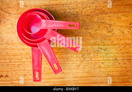 Red measuring cups in different sizes on a timber board Stock Photo