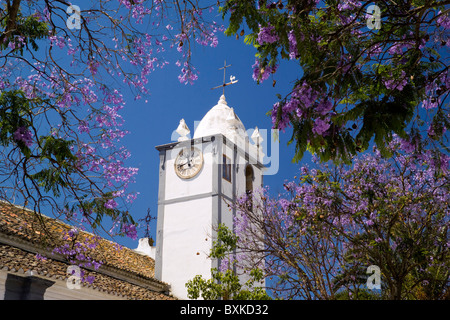 Moncarapacho Village Church Clock Tower And Jacaranda Tree In Flower Stock Photo