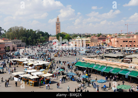 View across busy Djemaa el-Fna meeting place with a distant view of Kotoubia Mosque in Marrakech Stock Photo