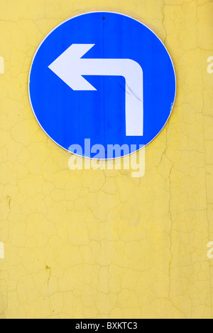 left turn sign on a yellow wall Stock Photo