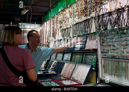 Seller showing jewelery to shopper, Temple Street Night Market,Yau, Ma Tei, Kowloon, Hong Kong, China Stock Photo