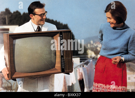 television / broadcast, tv serviceman in white smock bringing tv set Schaub Lorenz type Weltecho T 2450, Germany, 1966, technic, technics, historic, historical, reparation, reparations, old tv set, people, half length, 1960s, 60s, 20th century, customer, housewife, housewives, service, repaired, Additional-Rights-Clearences-Not Available Stock Photo