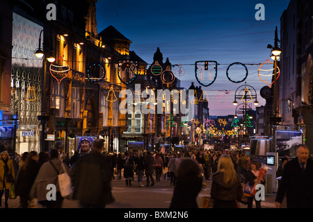 UK, England, Yorkshire, Leeds, Briggate, last minute shoppers below Christmas lights at dusk Stock Photo