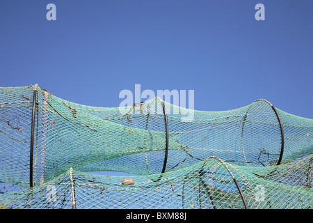 Drying fish trap nets on drying ground against a blue sky with