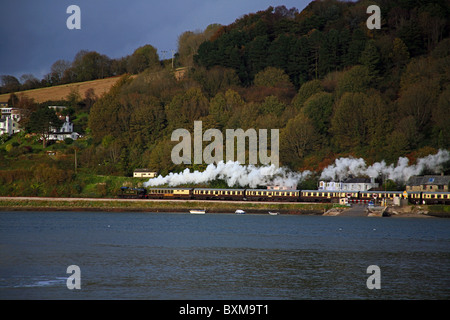 A Paignton & Dartmouth steam train climbs away from Kingswear next to the River Dart at Dartmouth, Devon, England, UK Stock Photo