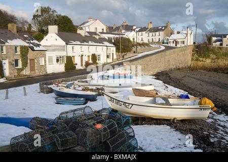 Moelfre Isle of Anglesey North Wales UK December Lobster pots and boats on snow covered beach of  small fishing village snow is unusual on Ynys Mon Stock Photo