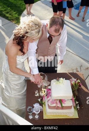young bride and groom cutting wedding cake Stock Photo