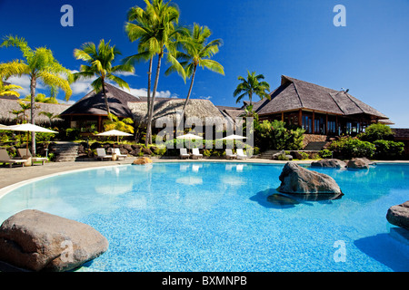 Palm trees hanging over stunning hotel pool with rocks Stock Photo