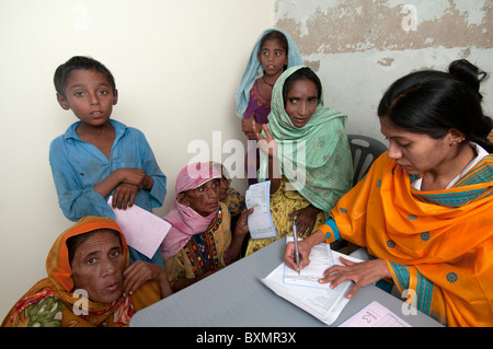 Pakistan after the flood. Doctor Sahira Bano examines a patient watched by her family Stock Photo