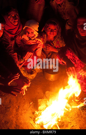 Sindh province. Railway camp for displaced people. People without tents warm themselves by a fire. Stock Photo
