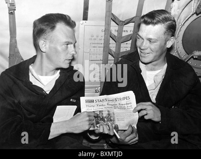 Combat Cargo, en route to Japan --- 1st Lt. Roy M. Jones (left) and Sgt. Gerald Neighbors looks over a Seoul edition of Stars Stock Photo