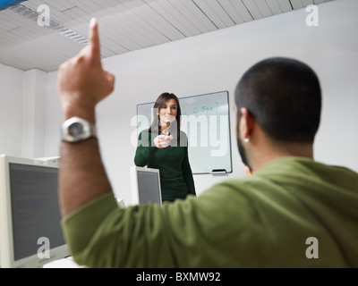 Computer class with hispanic student asking question to female teacher. Horizontal shape, focus on background Stock Photo