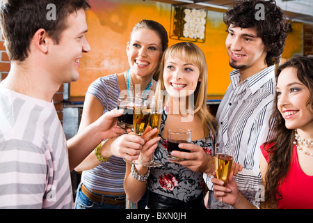 Four people gazing at handsome man pronouncing a toast Stock Photo
