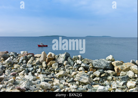 Fishing boat with Saltee Islands in background and sea defences, Kilmore, County Wexford, Ireland Stock Photo