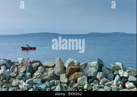 Fishing boat with Saltee Islands in background and sea defences, Kilmore, County Wexford, Southern Ireland Stock Photo