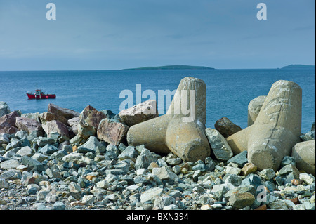 Fishing boat with Saltee Islands in background and sea defences, Kilmore, County Wexford, Ireland Stock Photo