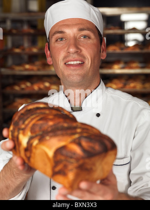 Smiling Baker a freshly baked loaf of sweet bread in his hands Stock Photo