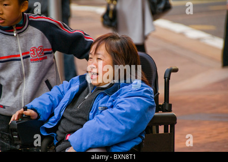 Handicapped oriental woman in wheelchair on city street in San Francisco CA Stock Photo