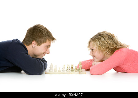 Attractive teenagers lying down using playing chess, isolated on white Stock Photo
