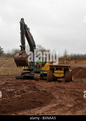 excavator digger and dumptruck on road building site uk in winter Stock Photo