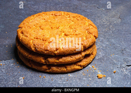 Three ginger biscuits stacked and placed on a piece of slate Stock Photo
