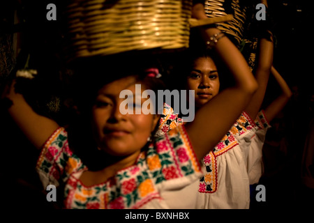Young women dressed with traditional regional clothing carry baskets in their heads during holy week celebrations in Oaxaca, Mex Stock Photo