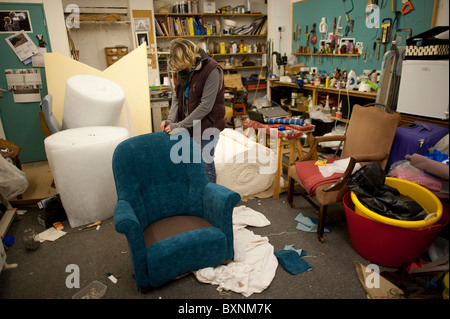 A self-employed woman upholsterer working in her studio workshop repairing an armchair, UK Stock Photo
