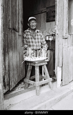 Man sitting in his doorway selling vegetables in Santiago de Cuba. Stock Photo