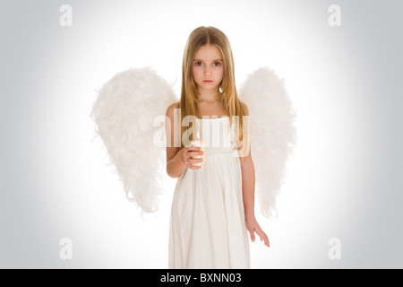 Portrait of innocent girl with candle and wings surrounded by holy light looking at camera Stock Photo